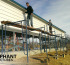 Metal carport construction with crew standing on scaffolding.