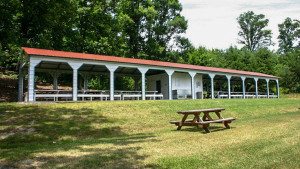 Eleven bay carport pavilion with picnic tables shown underneath.