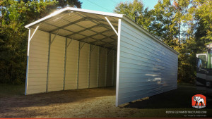 Covered carport metal building with vertical roofing and closed walls.